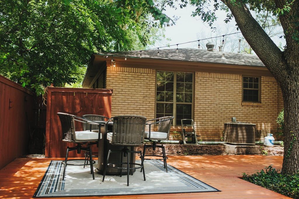 Une maison en briques dotée d’un patio aménagé avec du mobilier d’extérieur et un arbre.