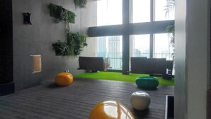 A modern indoor space with a wooden floor, large windows, and green plants. - Riveria City KL Sentral Luxury Apartment (Kuala Lumpur)