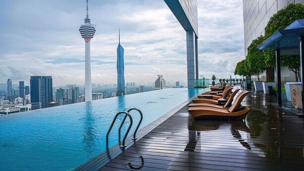 A rooftop infinity pool with lounge chairs, a city skyline, and a tall tower in the background. - Riveria City KL Sentral Luxury Apartment (Kuala Lumpur)
