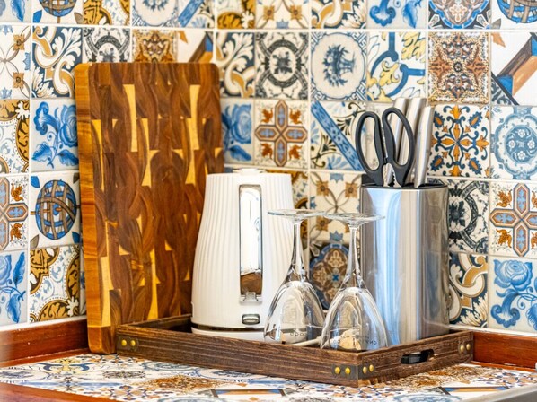 A kitchen counter with a coffee maker, a knife block, and a set of glasses.