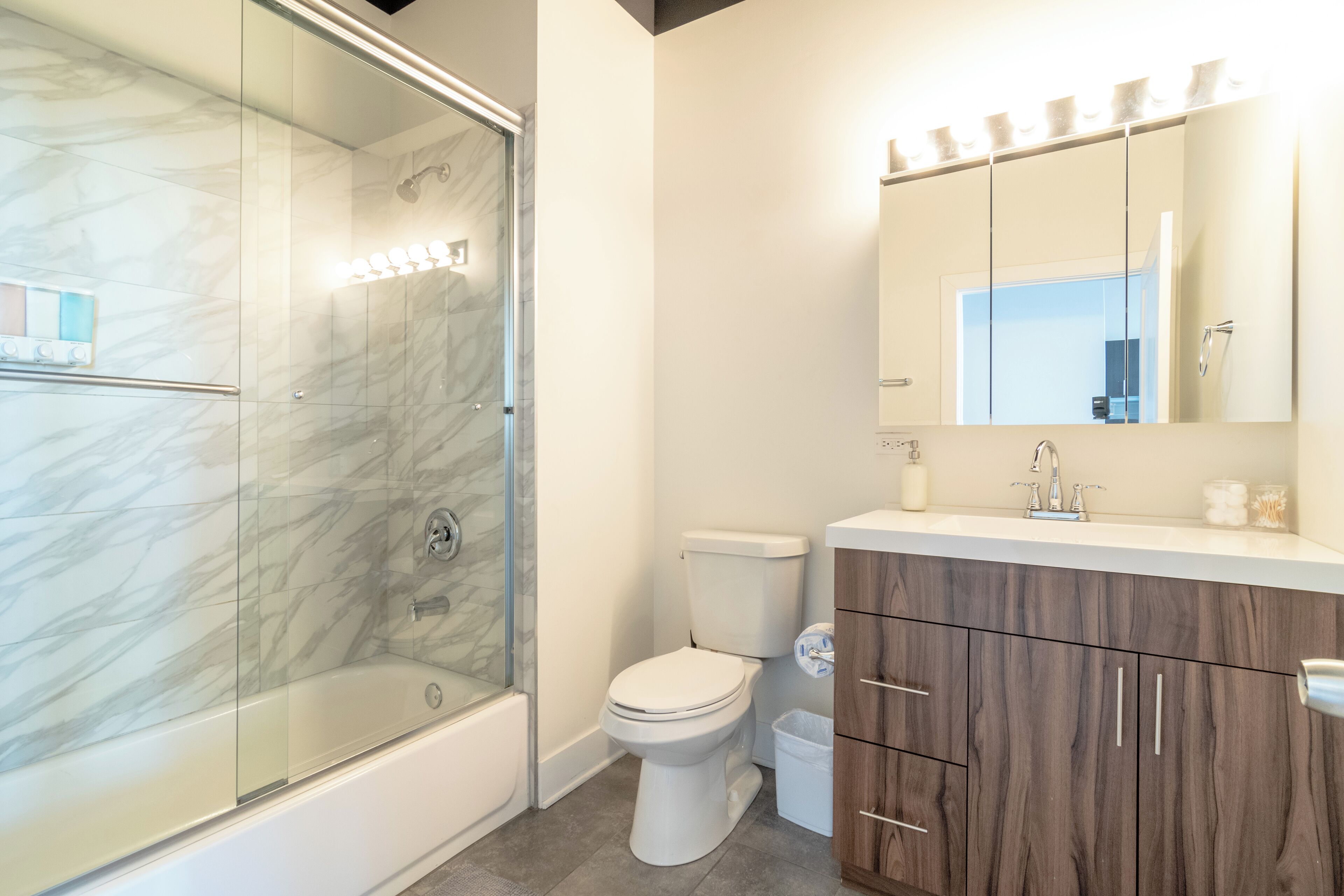 A modern bathroom with a glass-enclosed shower, a toilet, and wooden cabinets.