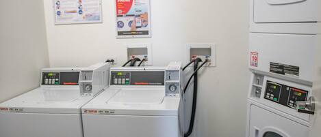 A laundry area with three front-loading washing machines and a stacked dryer.