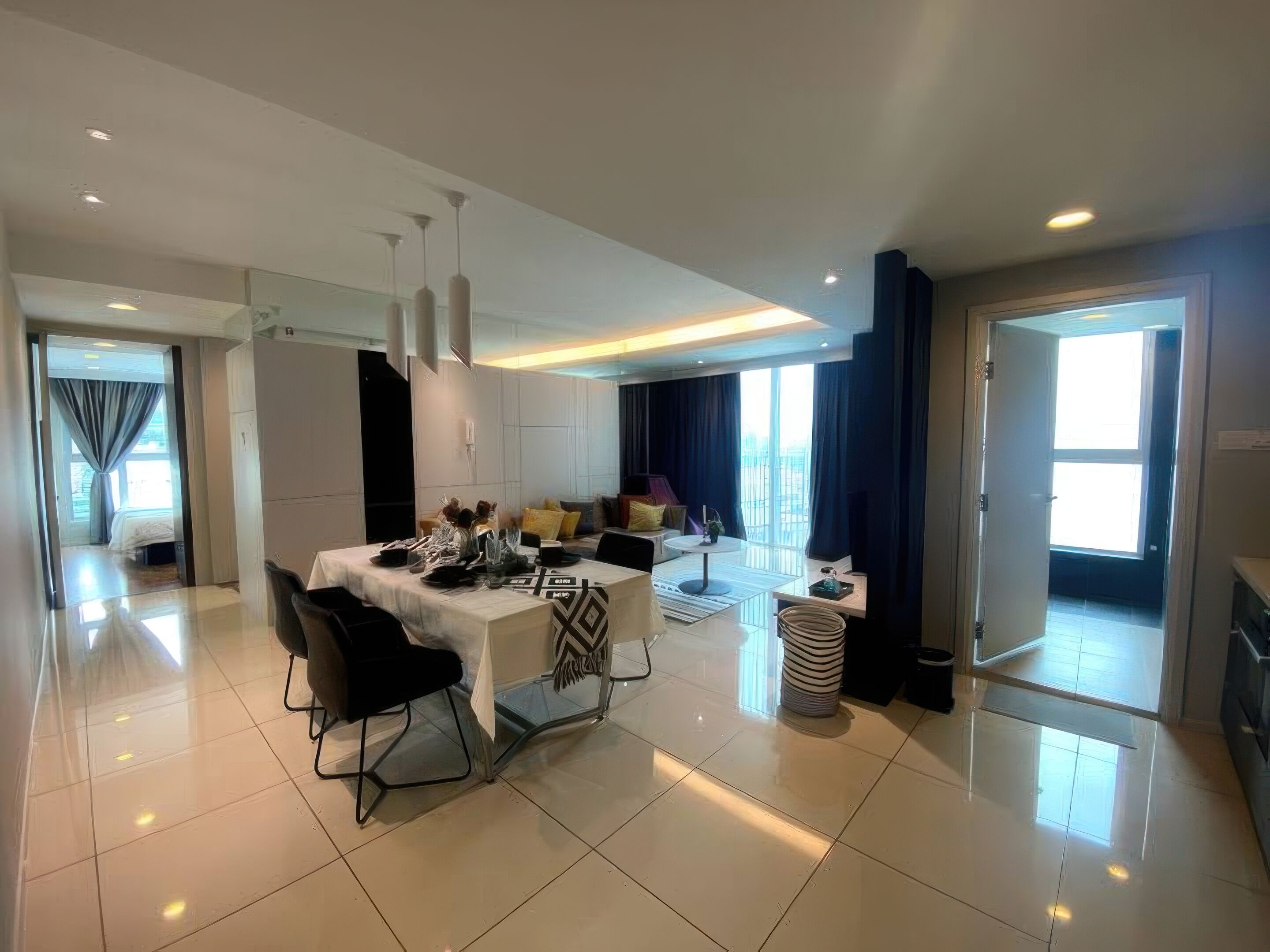 A modern hotel room with a dining area, a living space, and a balcony.