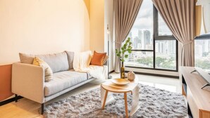 A modern living room with a sofa, a round coffee table, and a view of the city through large windows. - Opus Residences by Emily in Town (Kuala Lumpur)