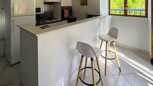 A modern kitchen with white cabinetry, a central island, and two bar stools.