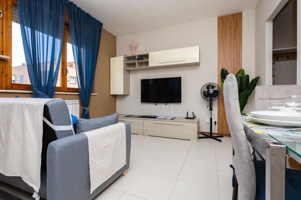 A modern living room with a sofa, TV, and dining area.