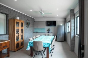 A modern kitchen with a dining area, featuring a large table, cabinets, and a ceiling fan.