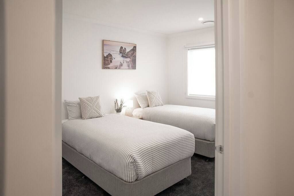 A bedroom with two beds, a window, and a wall-mounted picture.