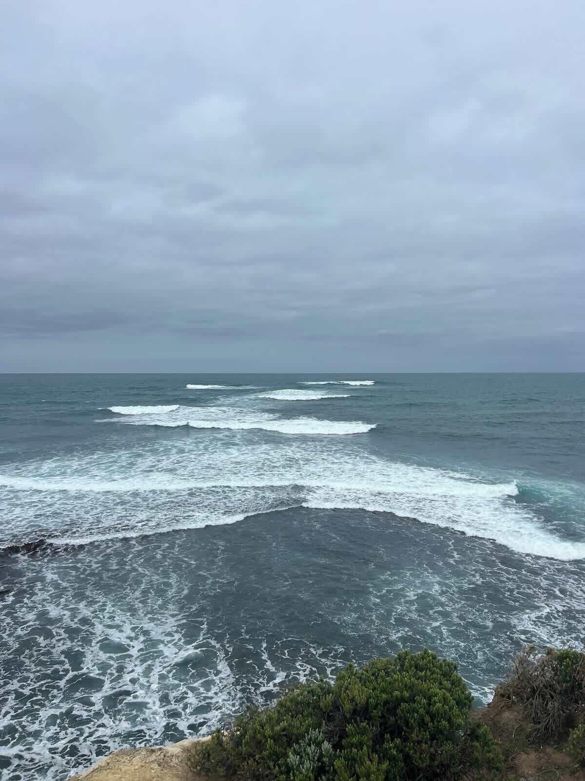 A coastal view with waves crashing onto a rocky shore.