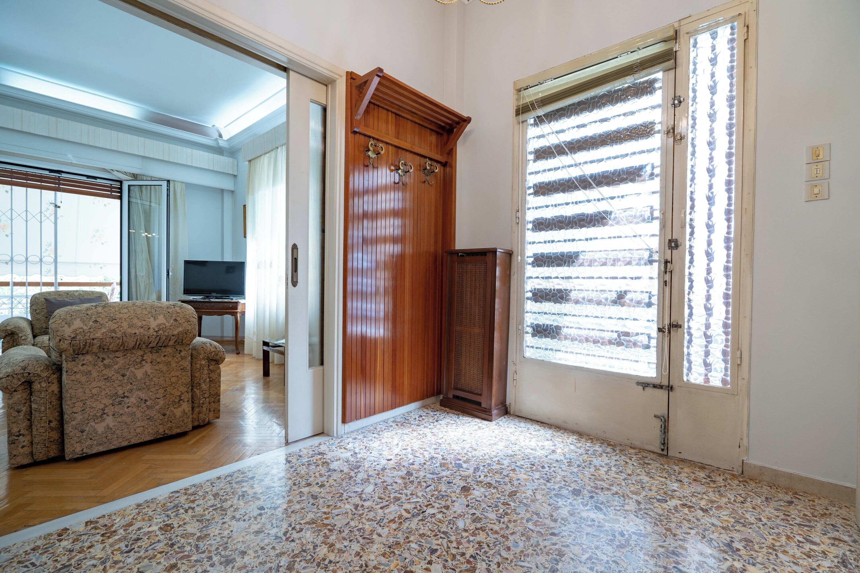 A spacious living room with a large sofa, a television, and a wooden cabinet.