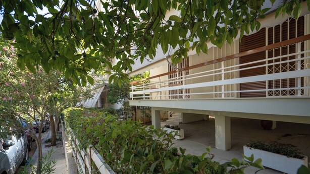 A building with a covered walkway, greenery, and a parked car. - Retro 2-Bdrm House Near Metro in Heraklion by ΜΡS (Iraklio)