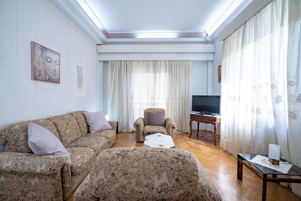 Una sala de estar con sofá, sillón y televisión sobre una mesa de madera.