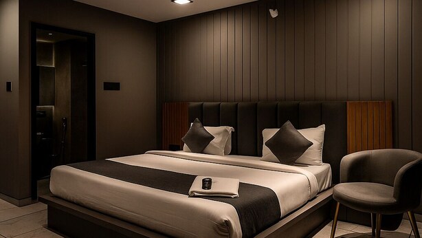 Une chambre moderne avec un grand lit, un ventilateur de plafond, un éclairage encastré et un fauteuil.