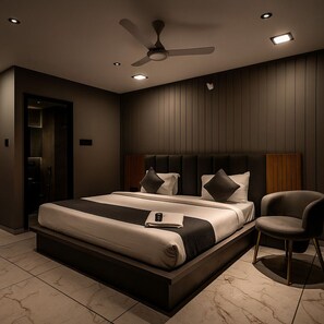Ein modernes Schlafzimmer mit einem großen Bett, einem Deckenventilator, Einbauleuchten und einem Sessel.