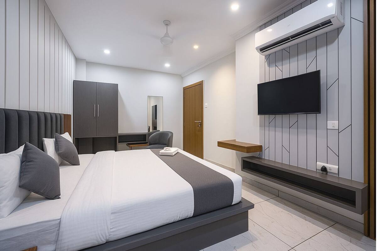 A modern hotel room with a large bed, a TV mounted on the wall, and a wardrobe.