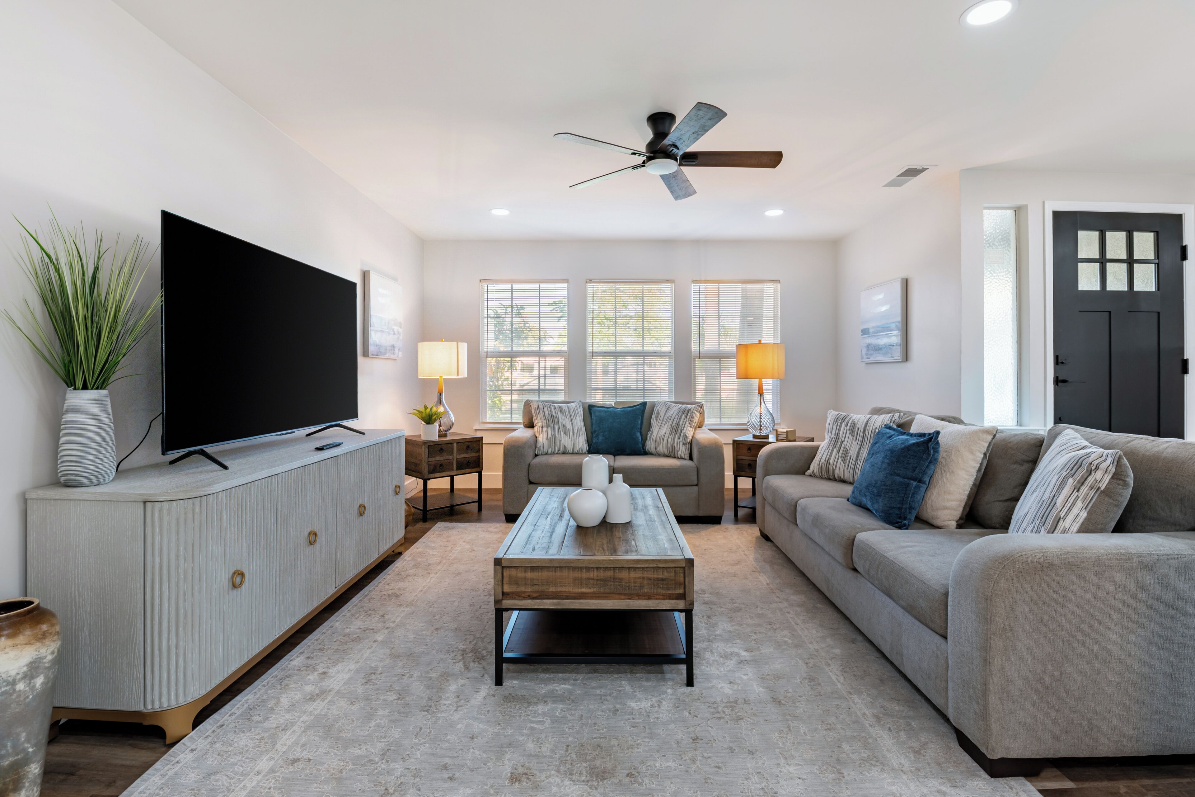 A living room with a TV, sofa, coffee table, and a ceiling fan.