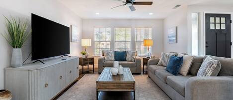 A living room with a TV, sofa, coffee table, and a ceiling fan.