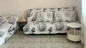A room with a pink and white wall, a round sign reading "BEACH HOUSE", a sofa with a nautical print, a small table, and a round white table. - Charming 2-bedroom terrace apartment in amazing Vir, Walk to North&South Beaches (Vir)
