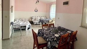 A dining area with a table set for four, a sofa, and a chair in the background. - Charming 2-bedroom terrace apartment in amazing Vir, Walk to North&South Beaches (Vir)