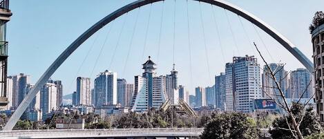 A cityscape with a prominent arched bridge in the foreground and high-rise buildings in the background.