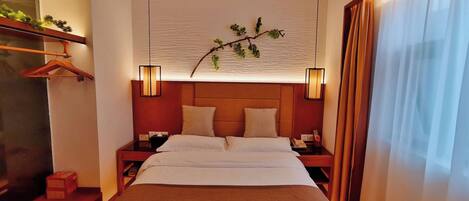 A hotel room with a bed, two bedside tables, a hanging plant, and a window with curtains.