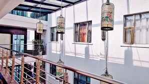 Un interior de varios niveles con escalera, ventanas amplias y jaulas de pájaros colgantes.