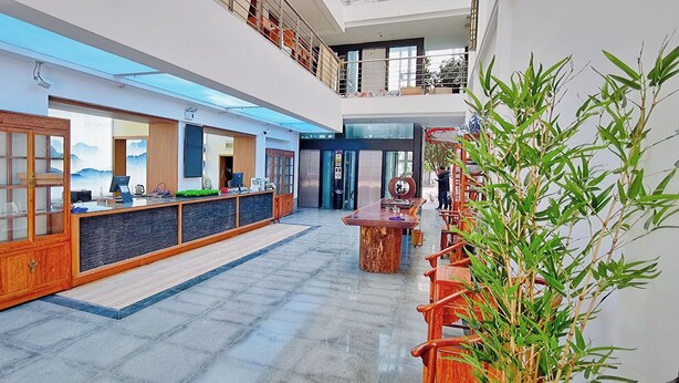 Un hall de hotel con mostrador de recepción, una escalera y una planta grande en maceta.