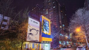 Un hotel con un gran letrero iluminado de diseño tradicional y un edificio moderno al fondo.