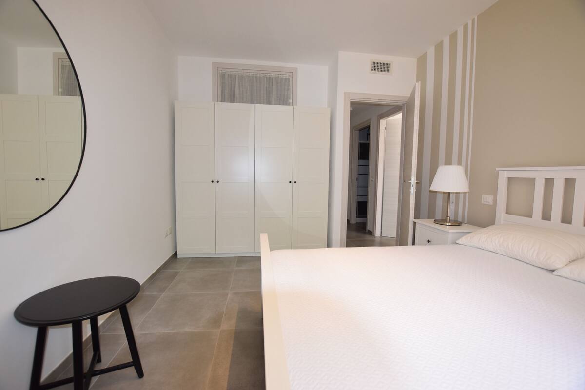 Une chambre à coucher comprenant un lit, une table de chevet, une lampe, une armoire et un miroir.
