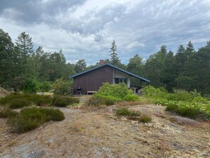 A rustic cabin with a covered porch, surrounded by dense forest. - 5 Person Holiday Home in Varmdo (Värmdö)