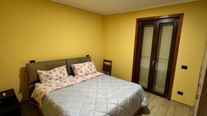 A bedroom with a bed, a nightstand, a wooden door, and a ceiling light.