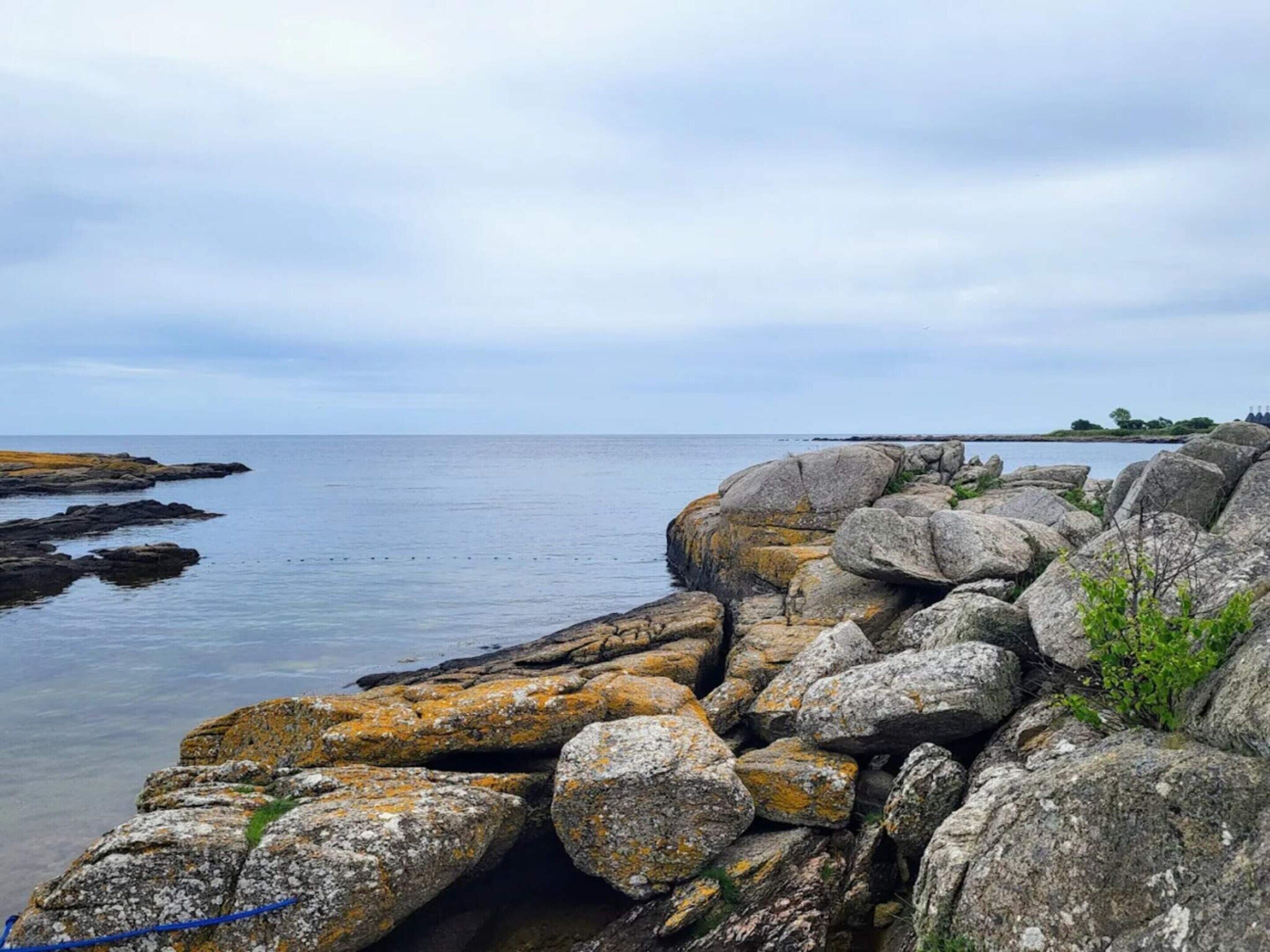 A rocky shoreline with large boulders and a calm sea.
