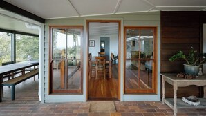 Una habitación amplia con un gran ventanal corredera que da a un espacio exterior, una mesa de comedor de madera y un banco.