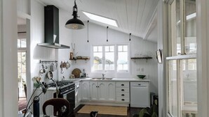 A kitchen with white cabinets, a stove, and a skylight.