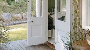 A wooden deck with a white door leading to a green interior.