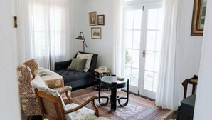 A cozy living room with a sofa, a patterned armchair, a small round table, and a bookshelf.