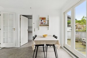 A dining area with a table, chairs, a bowl, and a shelf with items.