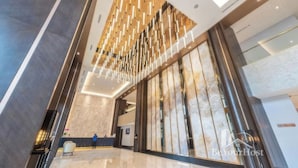A modern lobby with a high ceiling, a reception desk, and a large wall with a decorative panel. - KL Staycation Gateway Residences (Kuala Lumpur)