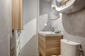 A modern bathroom with a toilet, sink, and shower area. - Charming Le Marais Mezzanine Studio (Paris)
