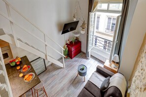 A modern apartment with a dining area, a sofa, and a TV mounted on the wall. - Charming Le Marais Mezzanine Studio (Paris)