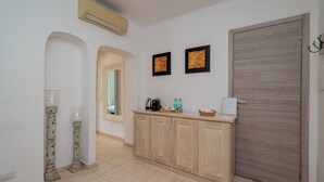 A hallway with a wooden cabinet, a door, and two framed pictures on the wall. - Locanda Tartarughino - Suite Luna (Porto Rotondo)