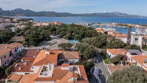 Une ville côtière aux bâtiments aux toits de tuiles rouges, dotée d’un port de plaisance et offrant une vue dégagée sur la mer.