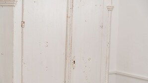 Une porte blanche présentant des signes d’usure visibles, notamment des rayures et des éraflures.