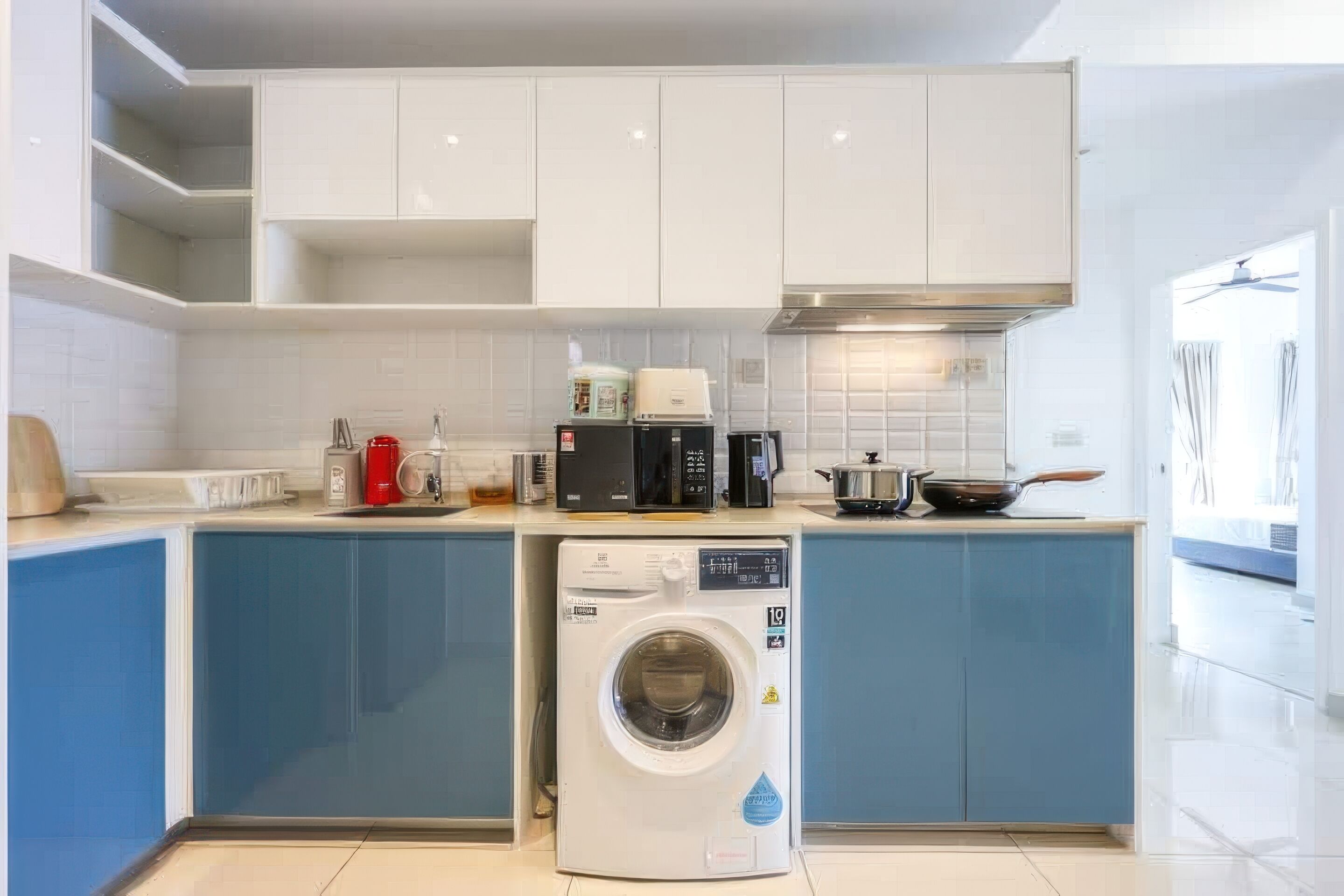 Una cocina moderna con armarios blancos, lavadora integrada y microondas.
