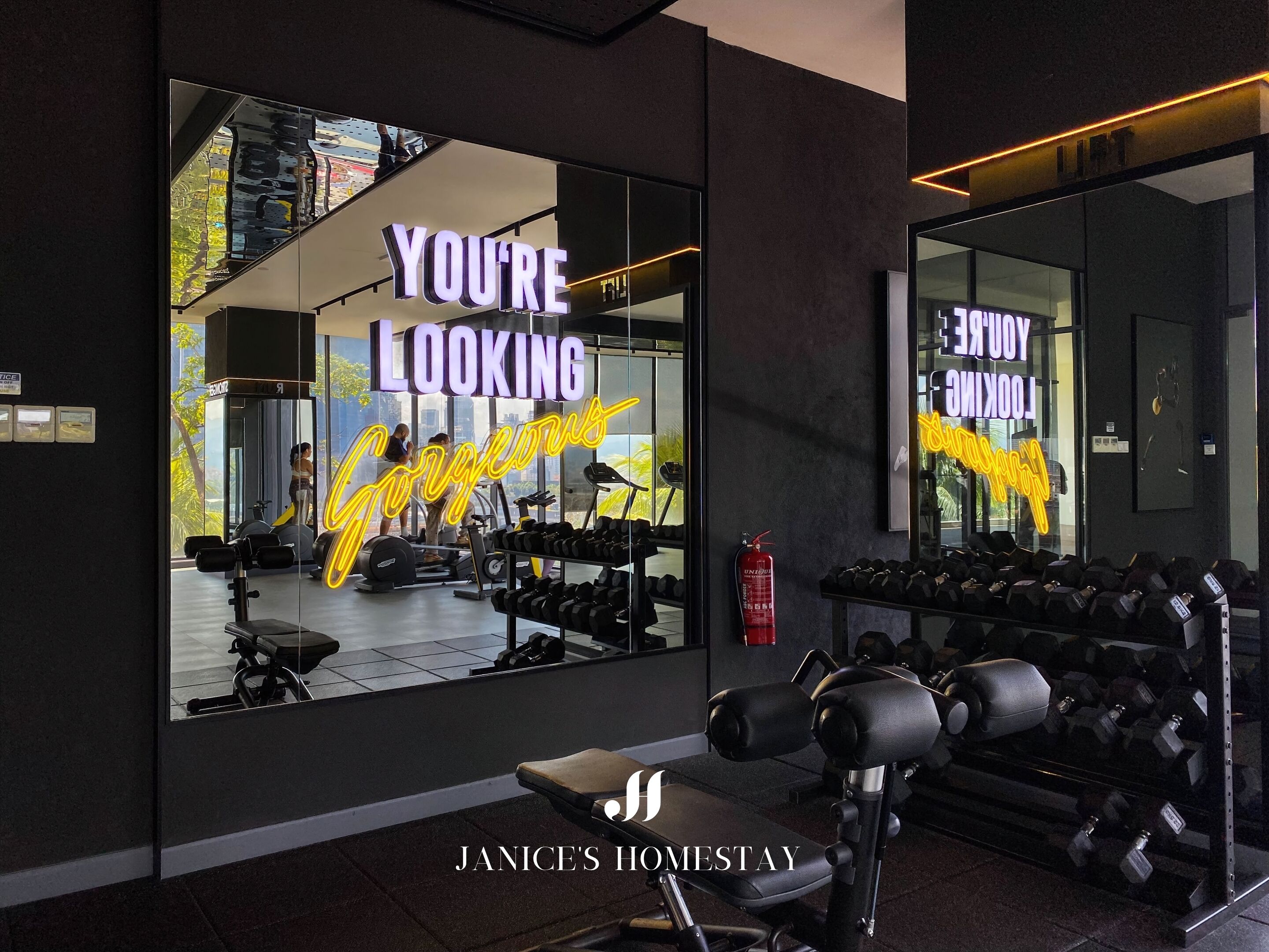 A gym with a large mirror reflecting the interior, motivational text on the mirror, and various exercise equipment.