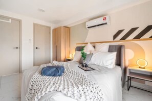 A modern bedroom with a bed, bedside tables, and an air conditioning unit. - Ciao Arte Cheras Apartments (Kuala Lumpur)