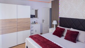 A bedroom with a bed, a wardrobe, a nightstand, a lamp, and a mirror.