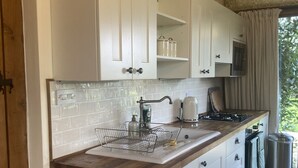 A modern kitchen with white cabinets, a wooden countertop, and a stainless steel sink.