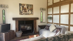 A cozy living room with a fireplace, a painting above it, and a large window with a view.
