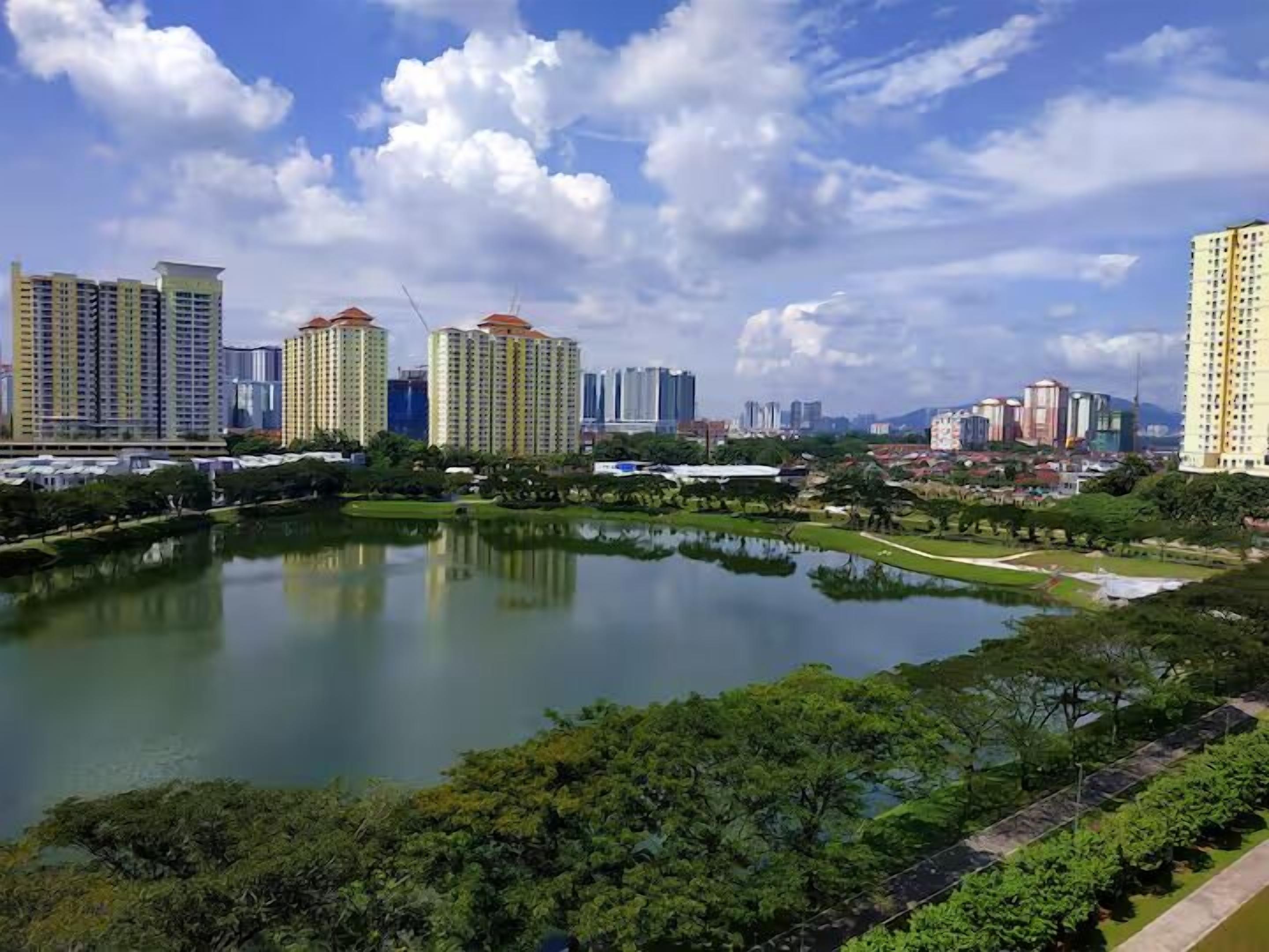 A cityscape with high-rise buildings, a central park with a pond, and surrounding greenery.